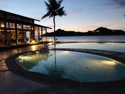 a swimming pool in front of a building with a palm tree at Island Paradise Resort Club in Koror