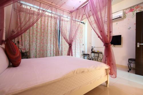 a bedroom with a canopy bed with pink drapes at Dear B&B in Hualien City