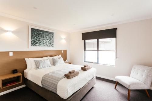 a bedroom with a large bed and a chair at Dolphin Lodge Albany - Self Contained Apartments at Middleton Beach in Albany