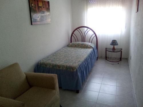 1 dormitorio con 1 cama, 1 silla y 1 ventana en Buquitos, en Atlántida