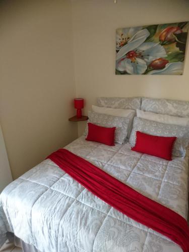 a bedroom with a white bed with two red pillows at Chanelle Self Catering in Bloemfontein