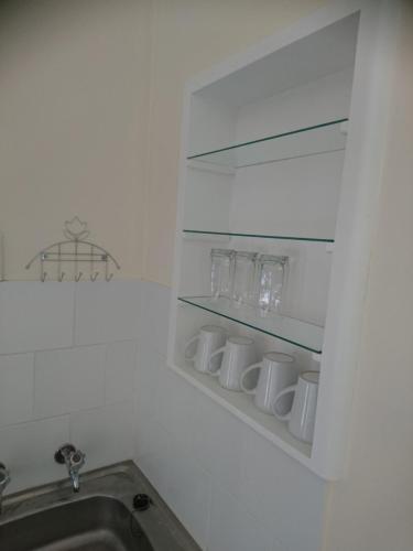 a kitchen with a sink and a shelf with glasses at Chanelle Self Catering in Bloemfontein