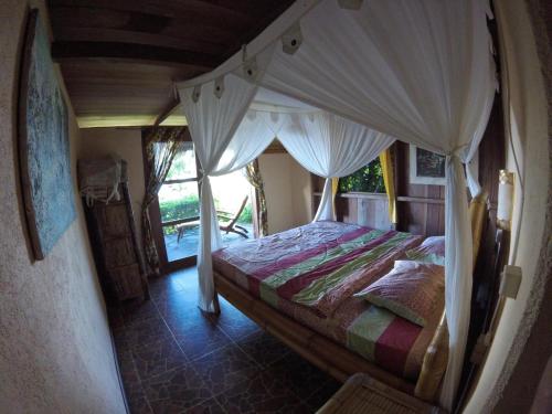 1 dormitorio con 1 cama con dosel en Rinjani Mountain Garden en Bayan