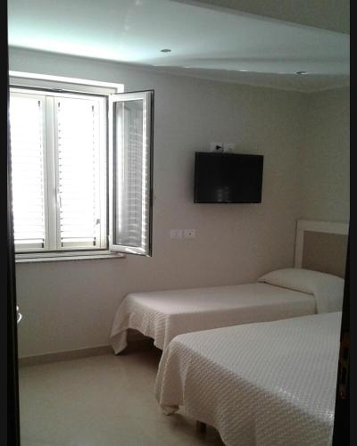a bedroom with two beds and a flat screen tv at Sweet Home in Falerna