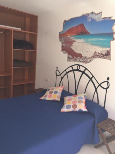 エル・メダノにあるApto Playa Medano ideal teletrabajoのベッドルーム1室(壁に絵画が描かれた青いベッド1台付)