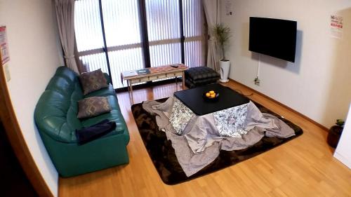 a living room with a green couch and a table at Tsudoh Stay Hikoso in Kanazawa