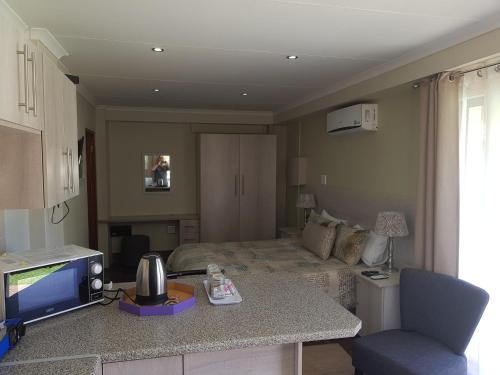 a room with a bed and a kitchen with a table at 12 On Vaal Drive Guesthouse in Vanderbijlpark