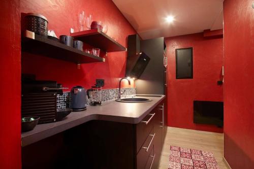 - une cuisine avec des murs rouges et un comptoir dans l'établissement Crystal Love Appart, à Pornichet