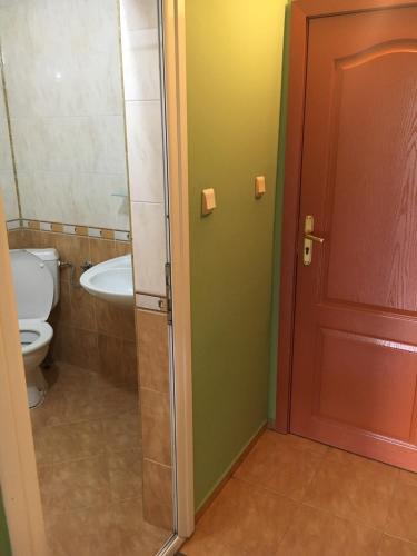 a bathroom with a toilet and a sink and a door at Arkadia Guest House in Primorsko