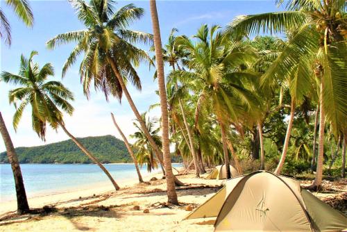 a tent on a beach with palm trees and the ocean at Aotea Camp'Inn Huahine in Fare