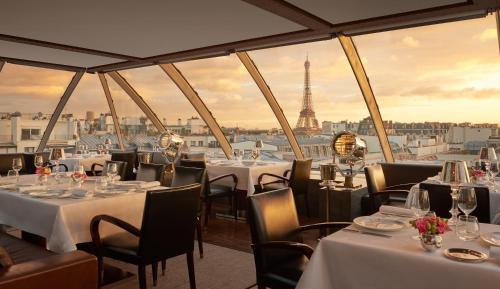 a restaurant with tables and chairs with a view of the eiffel tower at Hotel The Peninsula Paris in Paris