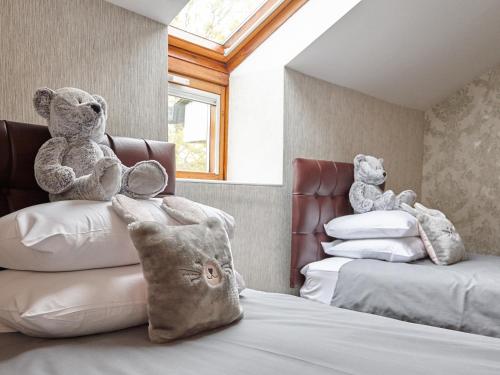 two teddy bears sitting on top of a bed at Hundith Hill Hotel in Cockermouth