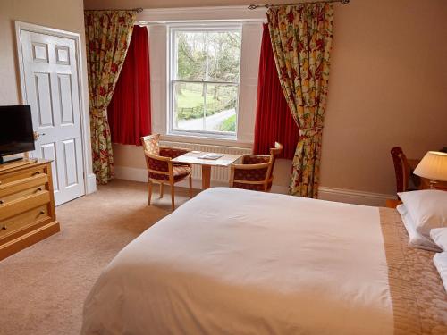 a bedroom with a bed and a desk and a window at Hundith Hill Hotel in Cockermouth