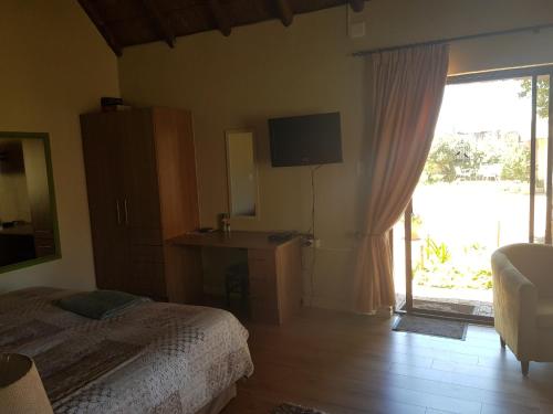 a bedroom with a bed and a sliding glass door at 12 On Vaal Drive Guesthouse in Vanderbijlpark