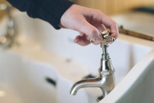 a person is holding a faucet on a sink at Bygdin Høyfjellshotell in Beitostøl
