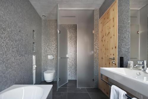a bathroom with a sink and a tub and a toilet at Alpine Lodge Chesa a la Punt in Pontresina