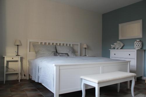 een slaapkamer met een wit bed en een witte kruk bij Ferienwohnung Lüntjenüst in Upgant-Schott