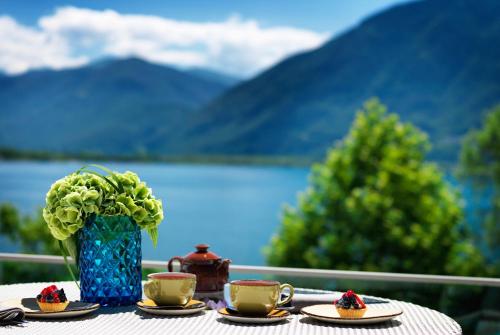 a table with two cups and a vase with flowers at Giardino Lago in Locarno