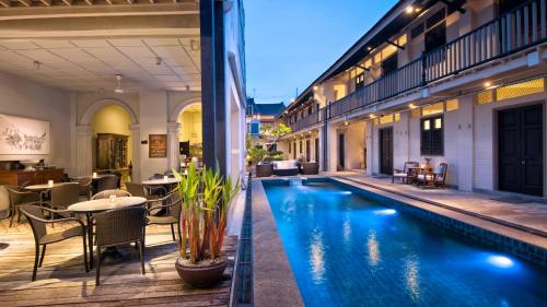 a hotel pool with tables and chairs and a restaurant at Noordin Mews in George Town