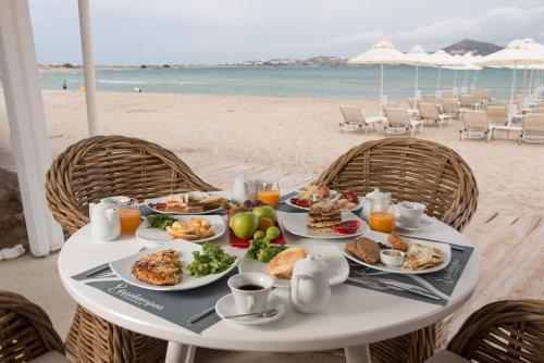 einen Tisch mit Teller mit Speisen am Strand in der Unterkunft Ippokampos Beachfront in Naxos Chora