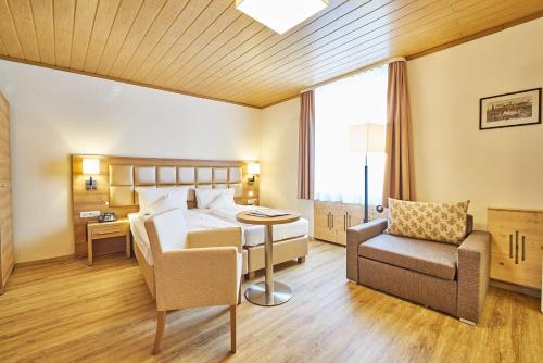 a hotel room with a bed and a chair at Akzent Hotel Goldner Stern in Muggendorf