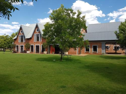 a large brick house with a tree in the yard at Millstream Inn guest house in Skeerpoort