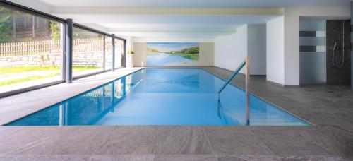 a swimming pool with blue water in a house at Gasthof Rabenstein in Sarntal