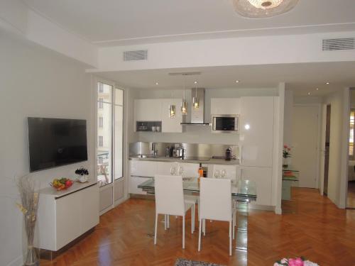 - une cuisine avec une table à manger et des chaises blanches dans l'établissement Le Massenet France, à Nice