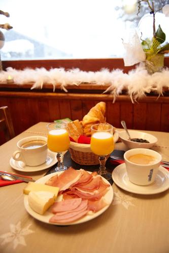 une table avec une assiette de nourriture et des verres de jus d'orange dans l'établissement La Gelinotte, aux Contamines-Montjoie