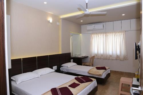 a hotel room with two beds and a window at Navaratna Palace in Belgaum
