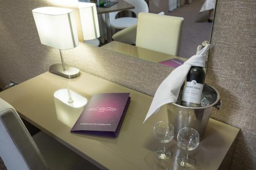 a table with a bottle of wine and glasses on it at Hotel Ameliówka in Masłów