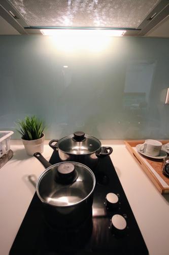 two pots on top of a stove in a kitchen at Solstice Service Apartment CYBERJAYA WiFi Netflix KLIA in Cyberjaya