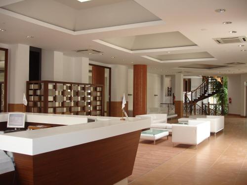 a lobby with a library with white furniture and shelves at Erytha Hotel & Resort Chios in Karfas