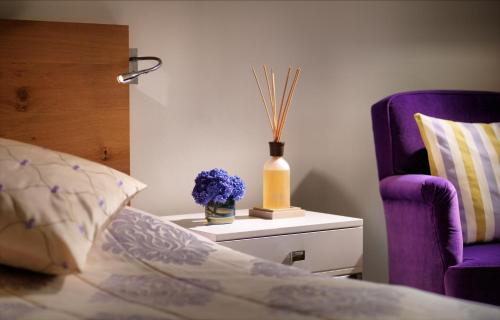 a bed with a purple chair and a vase of purple flowers at Giardino Ascona in Ascona