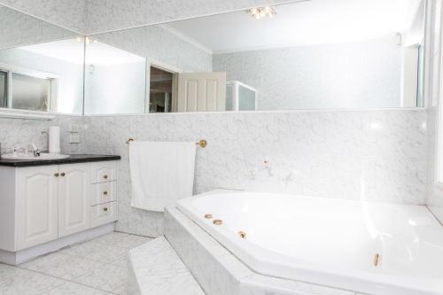 a white bathroom with a tub and a sink at Abbotsford Private Rooms & Pods - 15 Charles Homestay in Melbourne