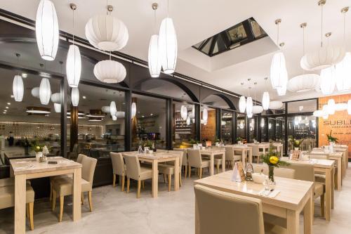 a restaurant with tables and chairs and chandeliers at Hotel New Skanpol in Kołobrzeg