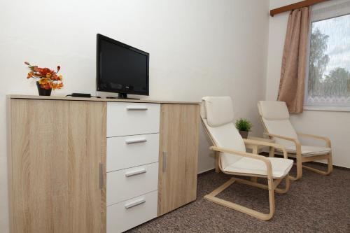 a room with two chairs and a tv on a cabinet at Penzion Starr in Havlickuv Brod