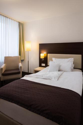 a hotel room with a large bed and a chair at Hotel Esplanade Dortmund in Dortmund
