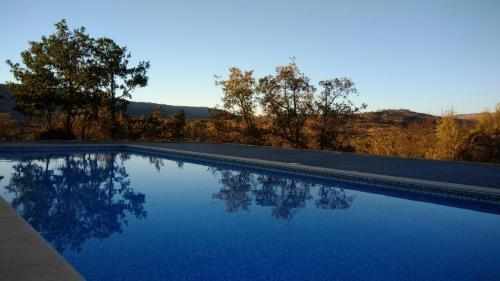 a swimming pool with blue water and trees in the background at Quinta dos Carvalhais - Serra da Estrela in Fornos de Algodres