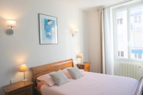 une chambre avec un lit avec des draps blancs et une fenêtre dans l'établissement ZePerfectPlace - Vieux Nice Garibaldi 3 chambres, à Nice