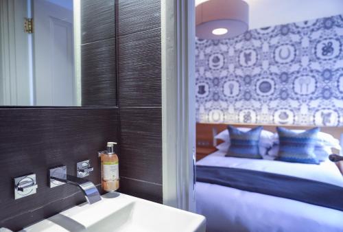 a bathroom with a sink and a mirror and a bed at Malmaison Cheltenham in Cheltenham
