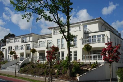 Un bâtiment blanc avec des fleurs devant lui dans l'établissement Dünenresidenz Königin Augusta - Apt. 15, à Binz