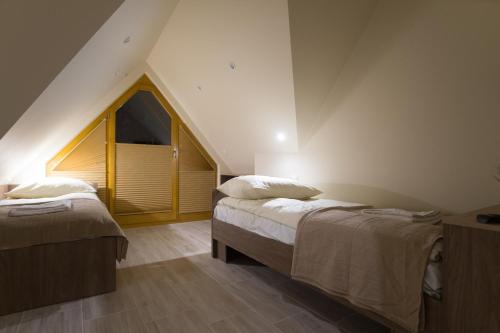 ザコパネにあるMłynek przy Równiのベッド2台と窓が備わる屋根裏部屋です。