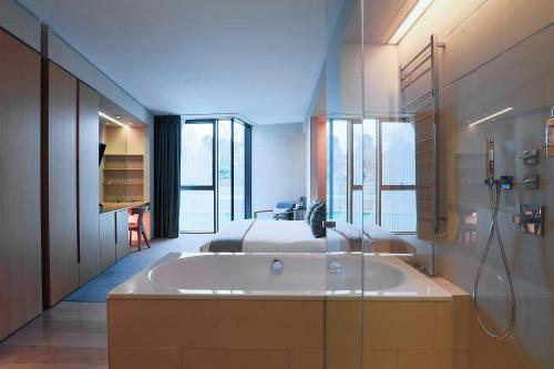 a bathroom with a tub and a bed and a shower at Malmaison Cheltenham in Cheltenham