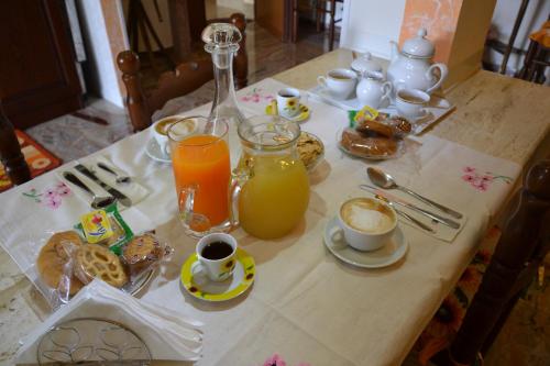 Una mesa con alimentos para el desayuno y jugo de naranja sobre ella. en Casa del Girasole, en Genazzano