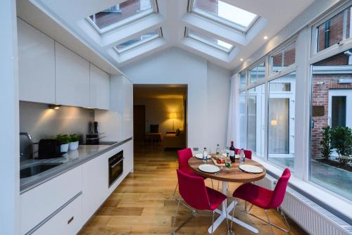 a kitchen and dining room with a table and red chairs at PREMIER SUITES Dublin, Ballsbridge in Dublin