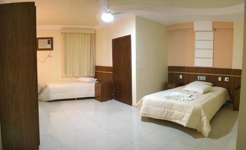 a hotel room with two beds and a window at Rede Andrade GV Center Hotel in Governador Valadares