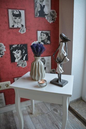 a table with a lamp and a vase with flowers on it at Ferienappartements "Landromantik" in Bautzen