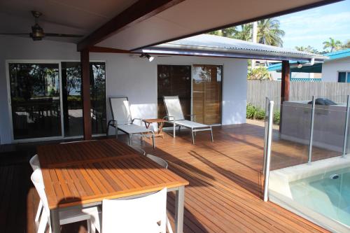 um deque com uma mesa e cadeiras ao lado de uma piscina em Banfields Retreat em Mission Beach