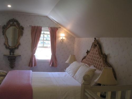 a bedroom with a bed and a mirror and a window at Annie's cottage in Kurrajong